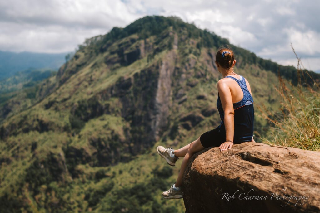 Woman sat on top of a rock looking out to green mountain